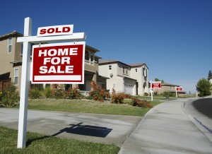 image of house with for sale sign planted in the garden, relating to mortgages